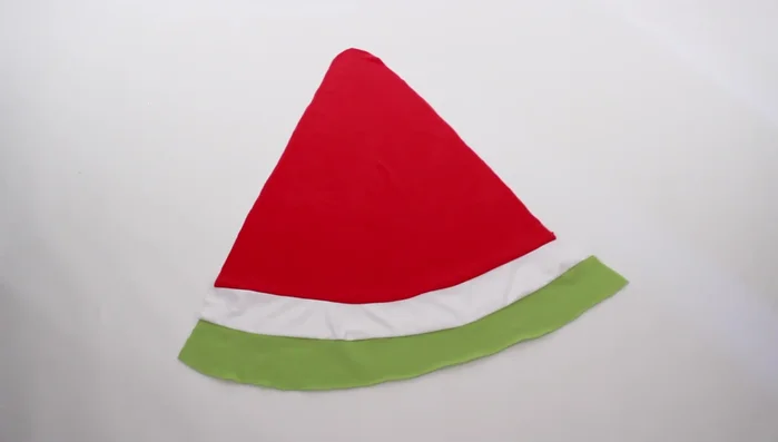 Design and cut out the facial details on paper, then transfer them onto black and pink fabric and cut out the fabric pieces.