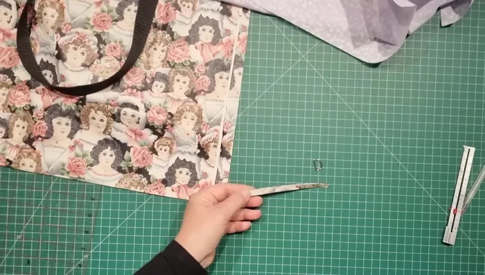 Attach D-ring Tab: Attach a small tab with a D-ring to one side of the handles.