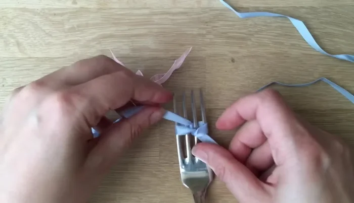 Pull the knot tight, keeping the ribbons in a 'V' shape to create a neat bow.