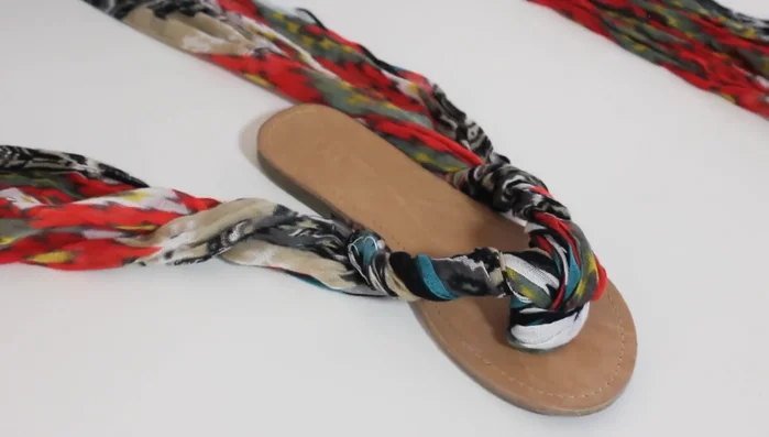 Tie the sandals around your ankle using a crisscross method: crisscross the fabric underneath your ankle, then behind the heel, and finally wrap around your ankle to secure.