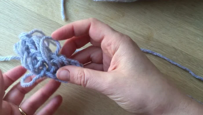 Add whiskers using a small piece of contrasting color wool. Create 2-3 small loops, insert them into the front of the mouse's face, and tie a knot to secure.