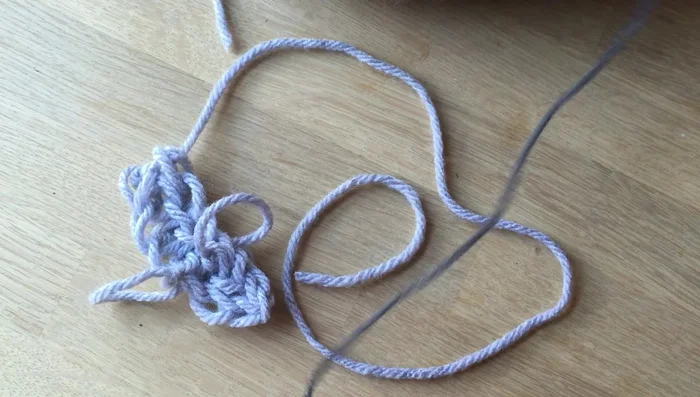 Add whiskers using a small piece of contrasting color wool. Create 2-3 small loops, insert them into the front of the mouse's face, and tie a knot to secure.